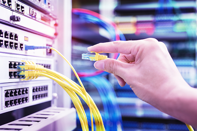 man working in network server room with network hub for digital communications and internet